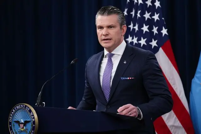 Pete Hegseth kürsüde konuşuyor, arkasında ABD bayrağı var. 28 Şubat 2026.
