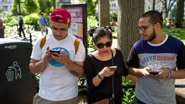 ثلاثة أصدقاء يحملون هواتفهم المحمولة