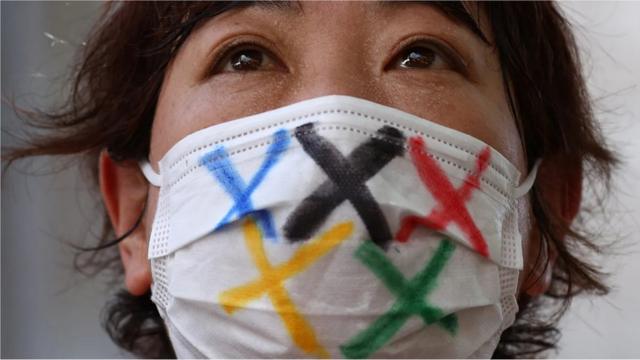 Torcedora usa máscara com o símbolo olímpico