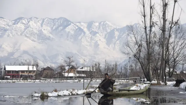 A Kashmiri boatman rows his boat on Dal Lake after fresh snowfall in Srinagar.