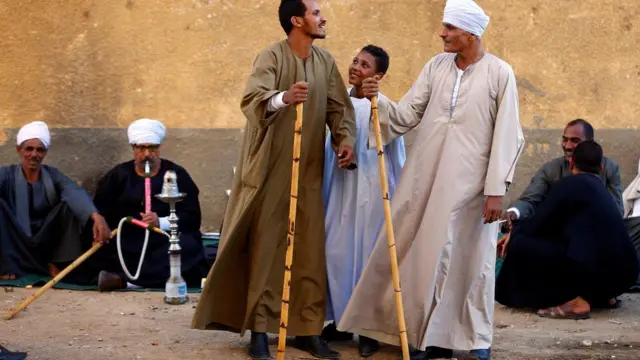 رجلان يقفان بتحدي قبل تأدية رقصة التحطيب