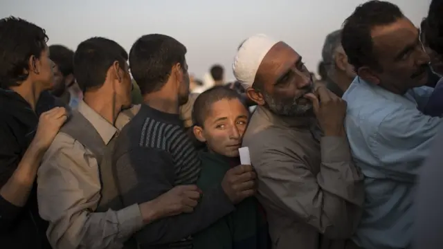 Fila de homens em campo de refugiados