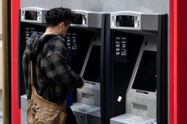 رجل أمام صرّاف آلي
