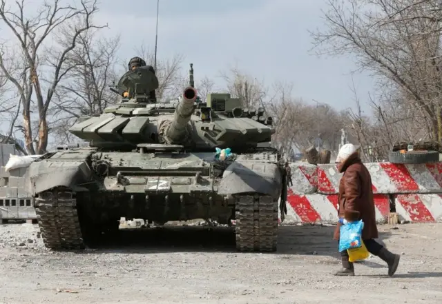 A local resident walks past a tank [letter Z can be seen on the front] of pro-Russian troops during Ukraine-Russia conflict in the besieged southern port city of Mariupol, Ukraine March 18, 2022.
