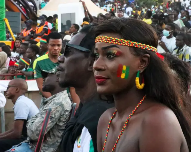 Umugore wisize irangi wambaye n'imitako y'amabara y'igihugu cye