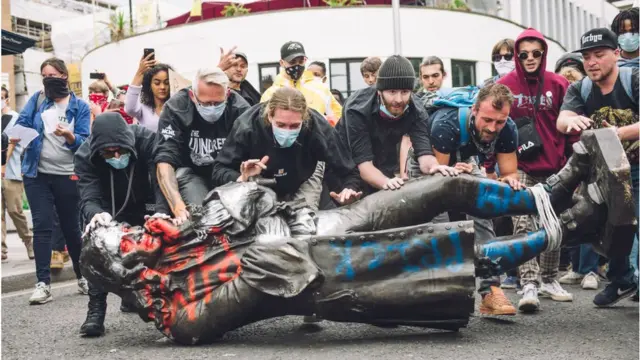 ব্রিটিশ শহর ব্রিস্টলে প্রতিবাদকারীরা ১৭শ শতাব্দীর ক্রীতদাস ব্যবসায়ী এওয়ার্ড কোলস্টনের মূর্তি তার স্তম্ভমূল থেকে নামিয়ে নদীতে ফেলে দেয়, ০৭/০৬/২০২০