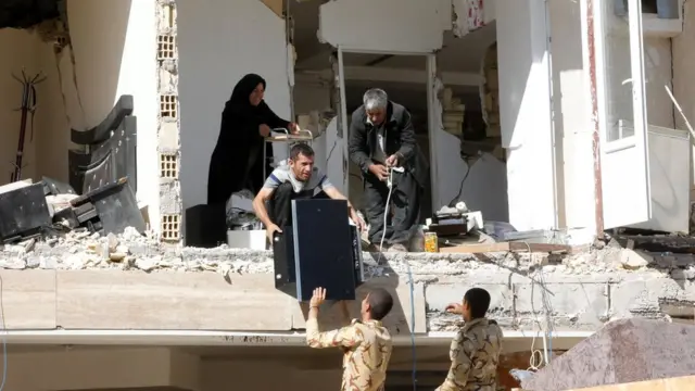 إيرانيون يجمعون بعض أثاثهم من منزل أصابه الزلزال