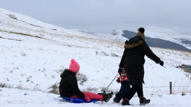Семья с санками на фоне гор.