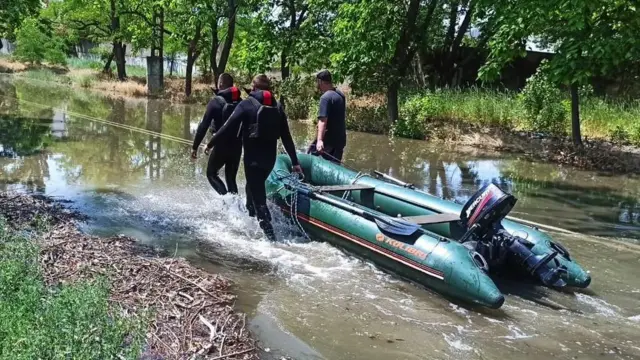 Rescue workers pull a dinghy through a flooded area