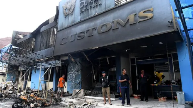 Warga merapikan tumpukan besi yang hangus terbakar di halaman Kantor Pengawasan dan Pelayanan Bea dan Cukai Jayapura, Kota Jayapura, Papua, Minggu (01/09)