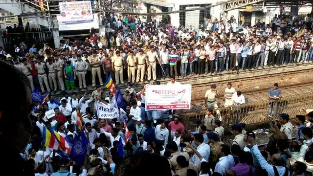 મુંબઈમાં રેલ-વે ટ્રેક પર પ્રદર્શ કરી રહેલા લોકોની તસવીર