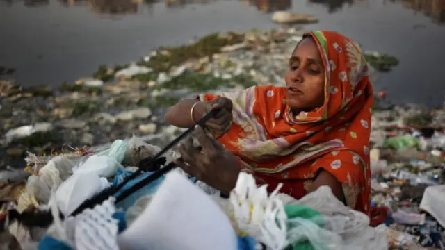এক মহিলা প্লাস্টিকের সামগ্রী কুড়াচ্ছেন।