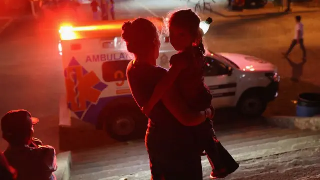 Una mujer y su hija en Honduras frente a una ambulancia