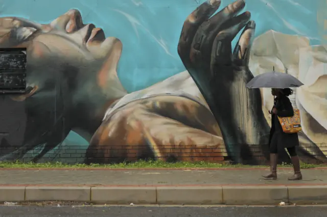 A woman holding an umbrella walks past a mural as heavy showers continue in Johannesburg, South Africa, 09 December 2019. Heavy rainfalls are predicted for the upcoming days for most of the inner country after a low pressure zone brought heavy rains last week.