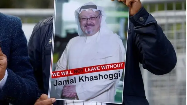 Umwigaragambya imbere y'ambasade afite ifoto y'umunyamakuru Jamal Khashoggi, yanditseho amagambo agira ati: "Ntituzava aha tutabonye Jamal Khashoggi"