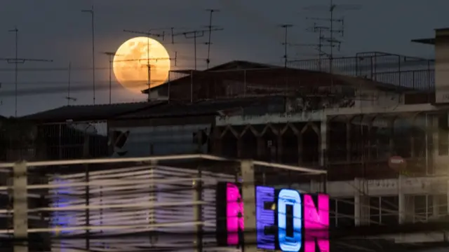 A full moon rises over the horizon above residential and commercial buildings in Bangkok on January 31, 2018.
