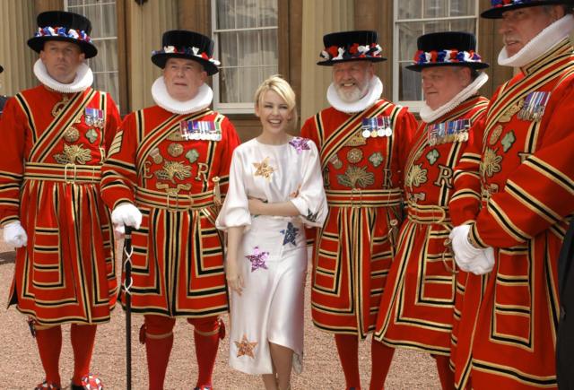 Australian pop singer Kylie Minogue (C) poses for photographs with Beefeaters after receiving her Order of the British Empire (OBE) from the Prince of Wales for services to music, at Buckingham Palace, in London, on 3 July 2008.