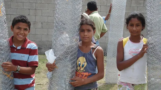 Niños con rollos de malla metálica para construir corrales
