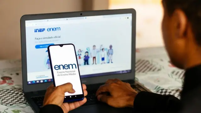 Homem adolescente com celular e computador com telas para inscrição do Enem