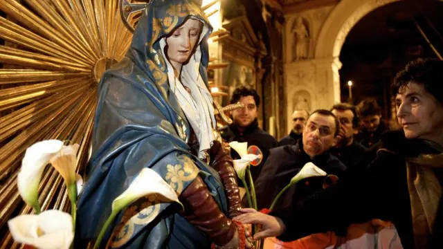 Mujer italiana le reza a la Virgen
