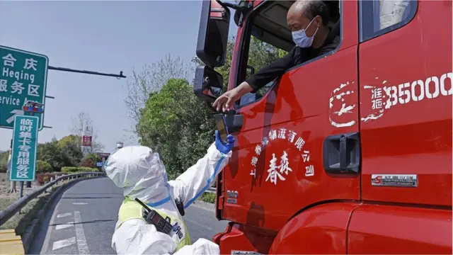A driver presents his negative nucleic acid test certificate for COVID-19 to a traffic police officer at a service station of G1503 Shanghai Ring Expressway as the city is under lockdown on April 11, 2022 in Shanghai,