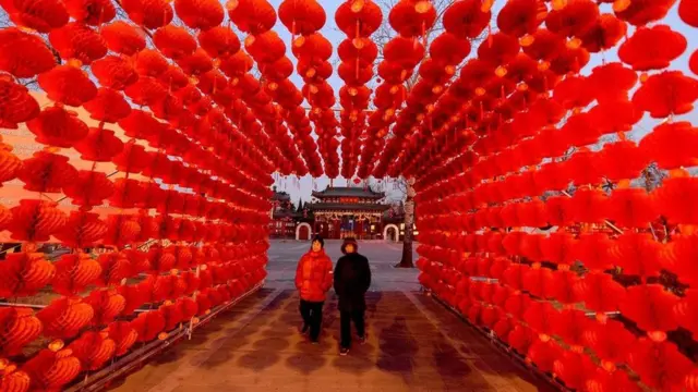 Dos personas cruzan por un túnel de lámparas rojas