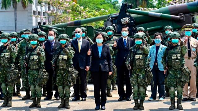 Tsai Ing-wen (no centro) aparece entre soldados e funcionários do governo posando para foto, todos de máscara