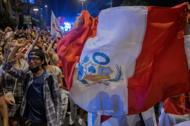 Un grupo de personas porta una bandera de perú
