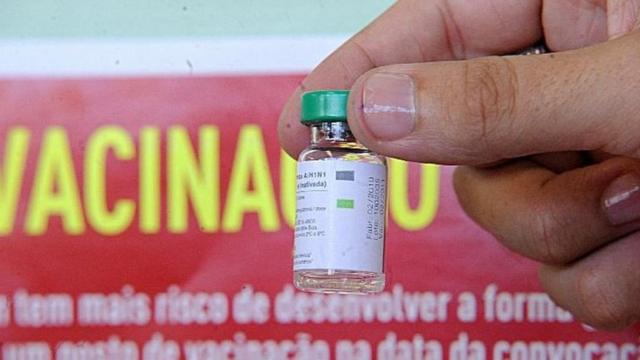 Mão segura frasco de vacina contra H1N1