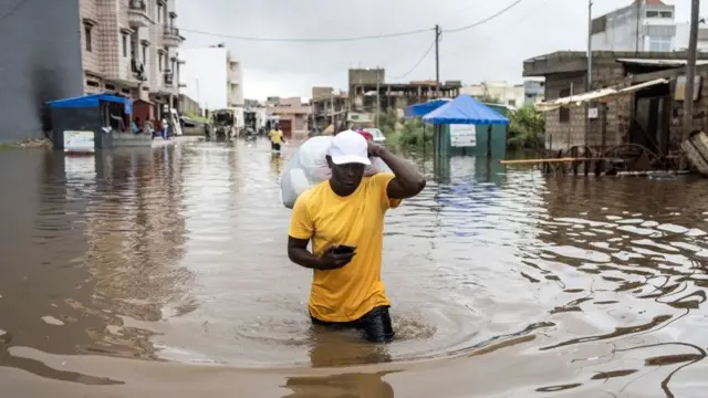 Un homme portant ses affaires dans un sac en plastic lors des inondations le 20 août 2021 à Keur Massar