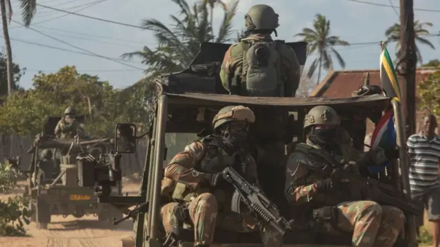 Un convoi militaire des forces de défense nationale d'Afrique du Sud roule sur une route de terre dans le district de Maringanha à Pemba, le 5 août 2021