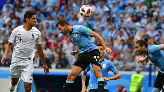 Pemain belakang Prancis, Raphael Varane (kiri) mencetak gol pertama, melampaui penyerang Uruguay, Cristhian Stuani (tengah) dan Martin Caceres.