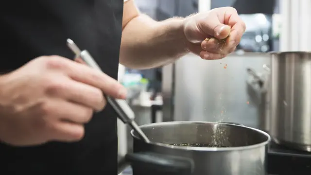 Un hombre cocinando una salsa.