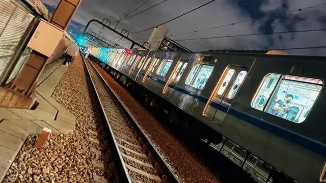 People walk along railway tracks after a knife attack on a Tokyo train