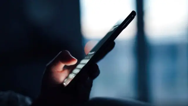 Image de la main d'une personne utilisant un téléphone portable