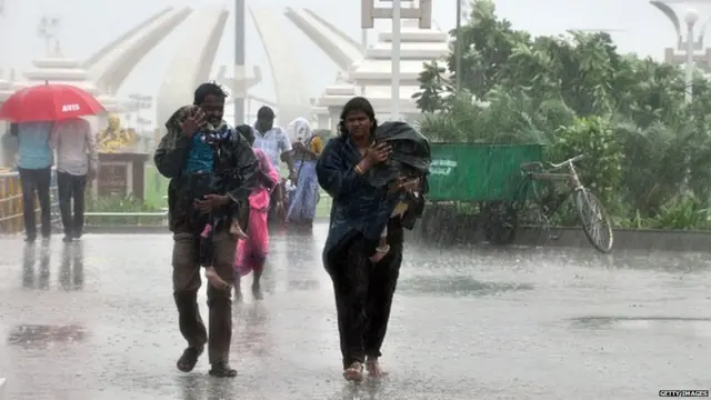 चेन्नईत आलेल्या वादळी पावसातून वाट काढताना लोक