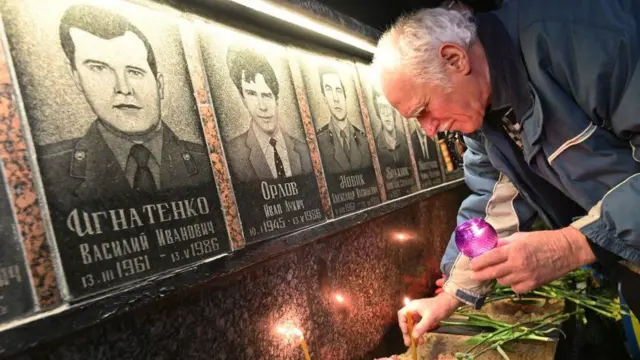 一位老人在切尔诺贝利核事故受害者像前点燃蜡烛