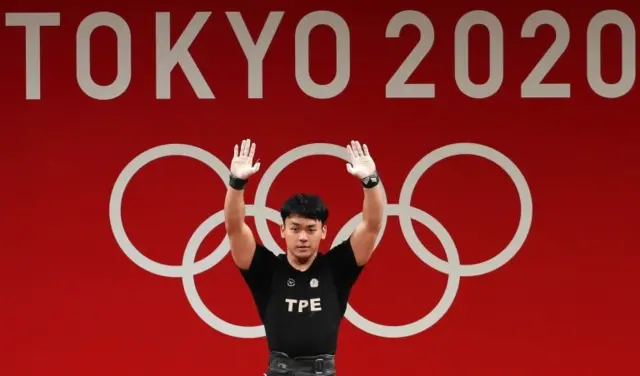 นักกีฬายกน้ำหนักจากไต้หวัน ฉากหลังเป็นคำว่าโตเกียว 2020
