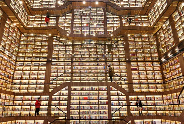 विशाल पुस्तकपसलमा उभिएर पुस्तक पढ्दै गरेका मानिसहरू