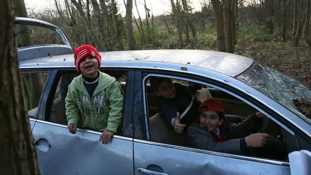 Niños juegan en un carro abandonado en el campo de refugiados de Dunkirk, en Francia.