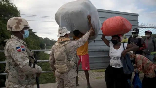 Portãoapp ludijogosacesso à fronteira. Homens e mulheres com sacolas são revistados por soldados dominicanos