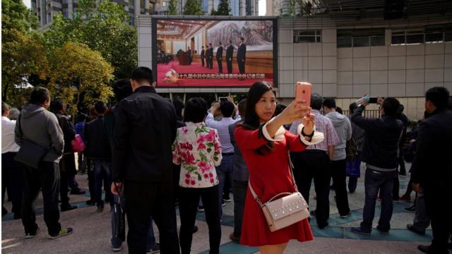在上海街头上，很多民众看政治局常委亮相的直播。