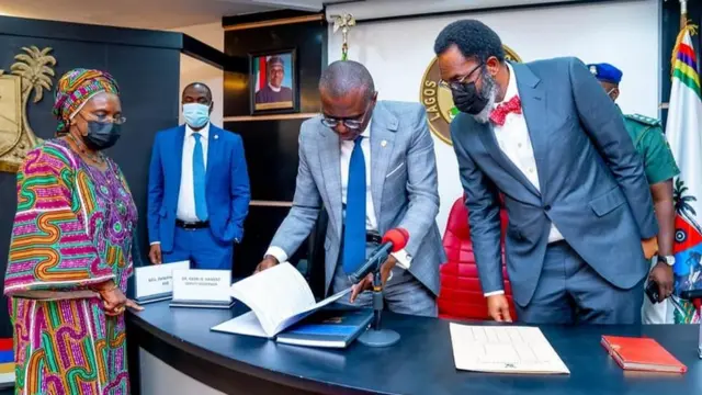 Gomina Sanwo-Olu n wo iwe abajade igbimọ oluwadii naa.