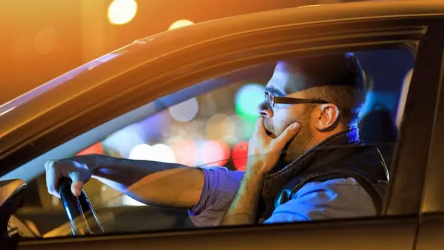 homem bocejando no carro