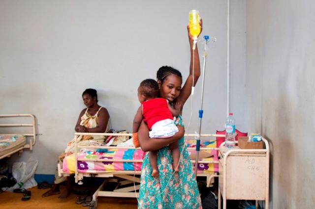 Une mère aide son bébé à prendre des médicaments par voie intraveineuse dans une clinique de Madagascar
