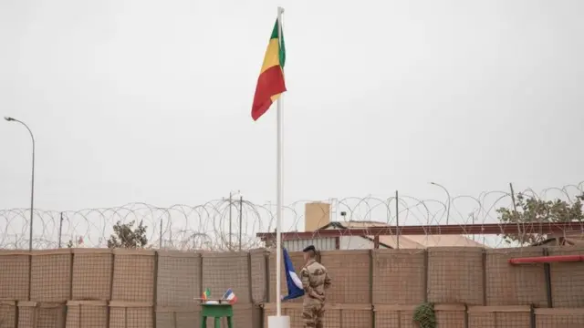 Le drapeau malien est hissé lors de la cérémonie de remise de la base militaire de Barkhane par les Français à l'armée malienne à Tombouctou, le 14 décembre 2021.