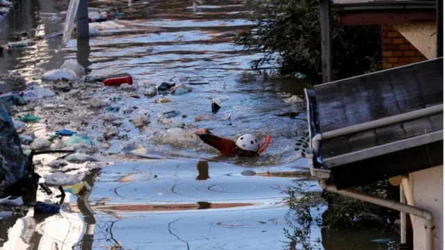 冠水した住宅地の道を調べる消防職員（13日、川崎市）