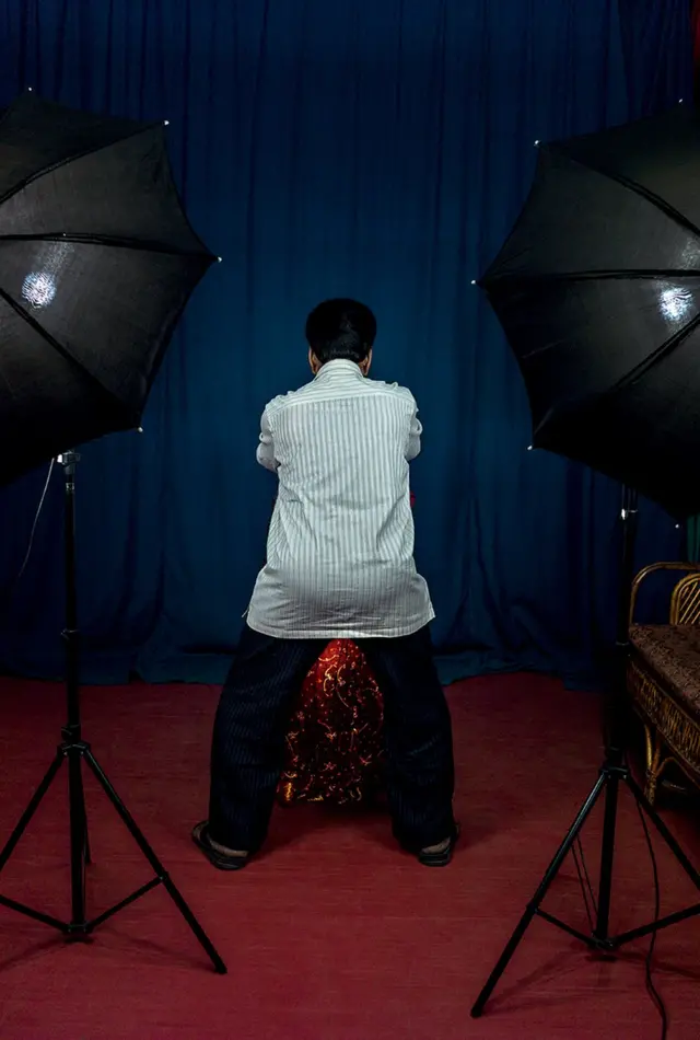 사진을 찍는 사진사의 다리 사이로 여성으로 추정되는 피사체의 전통 의상이 드러나 있다