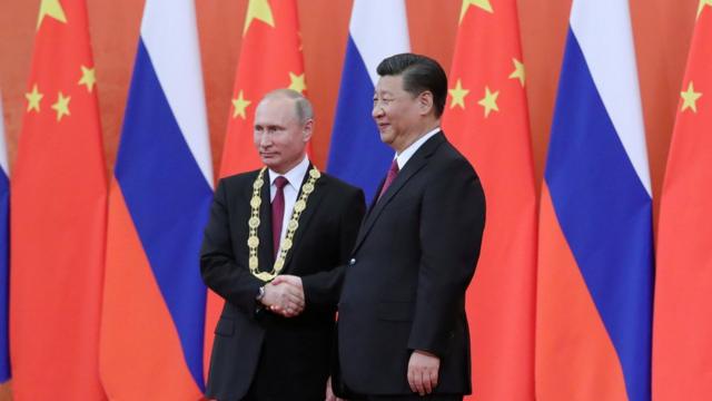 普京获颁中国友谊勋章后，与习近平握手。