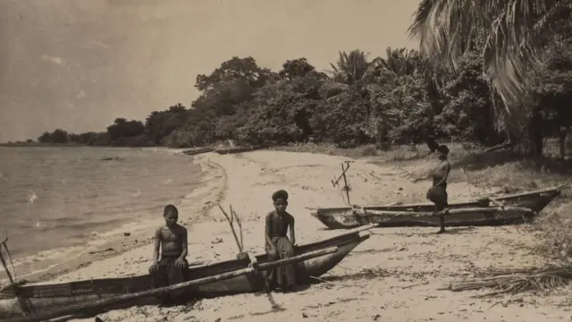 Anak laki-laki dengan perahu nelayan di pantai di Pulau Adonara